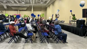 MUSC Senior Expo: a group of seniors doing chair yoga. 'Chair Yoga, get fit while you sit!'